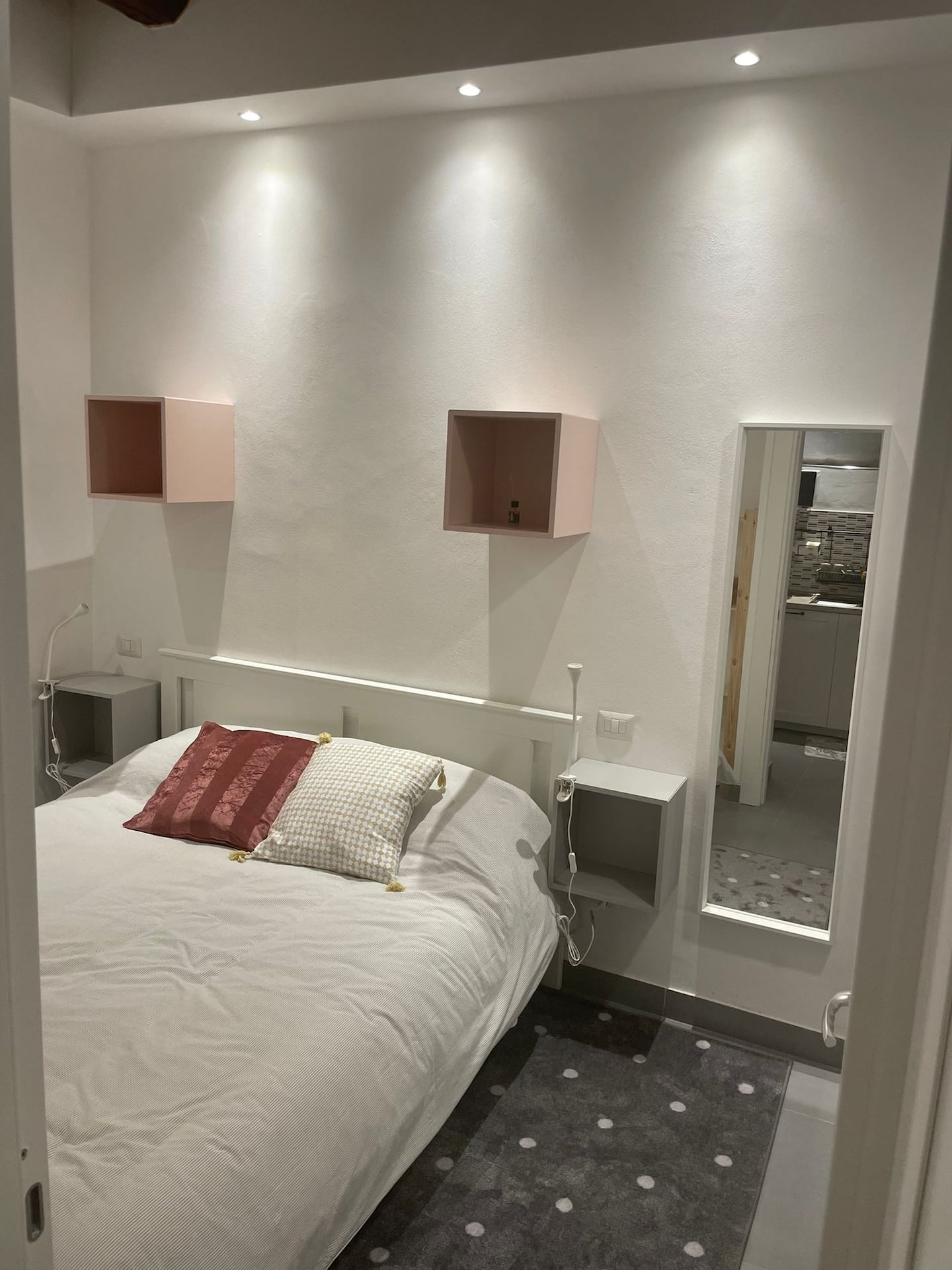 La zona notte del monolocale, con letto matrimoniale, nicchie sulla parete e travi a vista